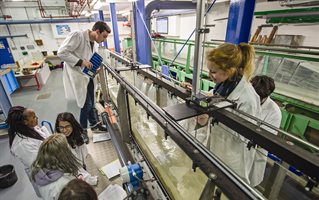 Students in white coats with a wave simulator