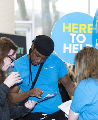 Student ambassadors helping a student holding signs that say Here to help