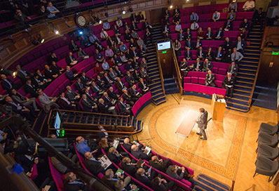 Man giving a talk in the middle of a crowd in the Royal Institution