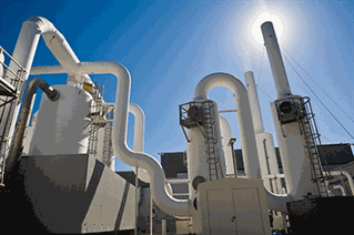 Water purification plant, white industrial pipes against bright blue sky.