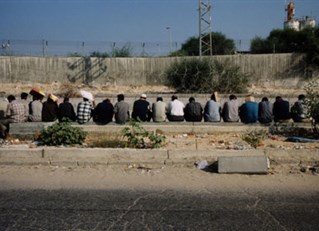 Row of seated figures, facing away in middle-eastern setting