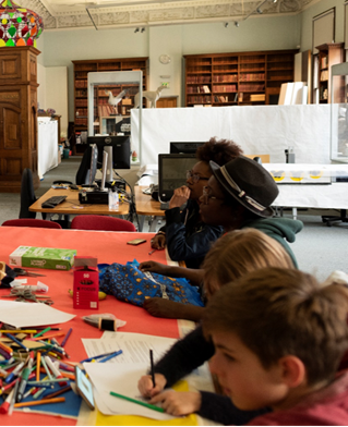 Young writers in a museum setting share stories of ethnic minority origins using cloth and textile props and writing materials
