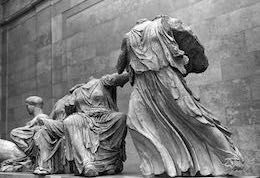 Black and white photograph of marble statuary, designed to fit triangular recess. Heads and limbs missing. Flowing robes.
