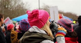 Close picture of person in crowd scene on a rainy day, wearing colourful hat and with a water bottleCrowd photo by Elyssa Fahndrich on Unsplash