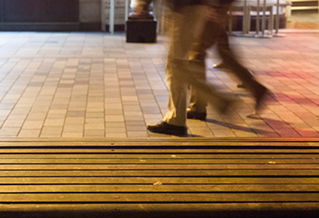 Photograph of moving legs passing a station bench
