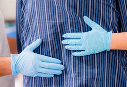 A pair of hands wearing medical gloves guiding an elderly person.