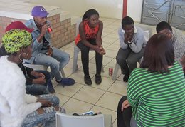 A group of young people sitting in a circle in a collaborative arts workshop in Leandra.
