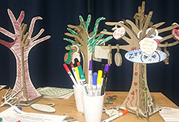 A group of trees made out of cardboard and decorated with felt pens, a couple of beakers full of pens and art materials depicting a resilience art workshop.