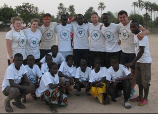 A group of Football 4 Peace coaches pose on a beach in The Gambia