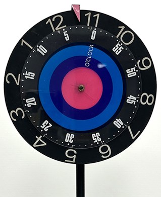 An acrylic and metal lamp clock with a blue, purple, and pink target in the centre. PCK-1-4-8. Paul Clark Archive, University of Brighton Design Archives.