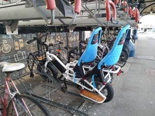 An e-bike in a bike storage rack with blue passenger seats visible