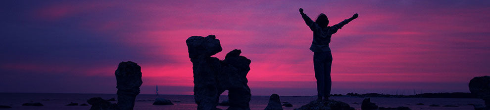 A person in silhouette standing up to welcome a morning sunrise