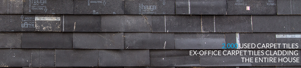 Strip of Brighton Waste House wall carpet tiles shows brick format. Printed text reads 2000 used carpet tiles ex-office carpet tiles cladding the entire house.