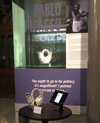 Museum display includes a 3D replica of a Picasso ceramic, designed to be held, in front of a glass case with the original. Digital screen shows the technologies used in production.