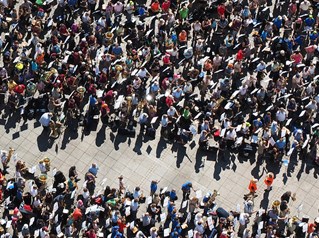 Aerial view of crowd gathered either side of a roadway. Courtesy of Hans Braxmeier and Pixabay.