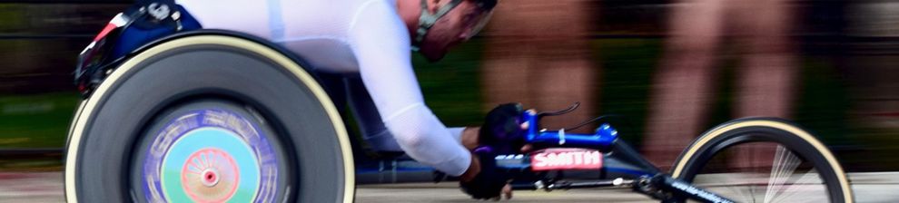 Panned photograph of wheelchair road racing athlete with blurring in background and large rear wheels. Image courtesy Joseph Two.