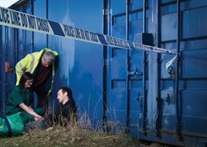 Paramedic and medical professionals attend an unconscious person with a Police line do not cross tape running across the foreground