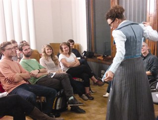 Presentation room at the Victoria and Albert Museum. Seminar group with researcher in centre wearing long grey dress. Part of design research seminar series conducted by Guy Julier and Lucy Kimbell.