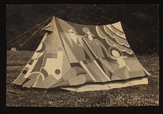 Black and white photograph of traditional tent with striking decoration showing two adults and a child in a stylised landscape. Made by the Kibbo Kift. Courtesy of Annebella Pollen and the Kibbo Kift Foundation.