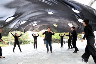 Performance directed by Alice Fox at Korean Disability Arts Festival. Vast black fabric square billows into the air above a group of artist participants, each of whom now moves inwards, under it.