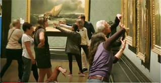 Image shows old master gallery with gold frames, visitors holding stylised poses of pointing togther, framing with fingers and crouching to peer at the pictures. An intervention performance work at the National Gallery, London, by Alice Fox, Looking and