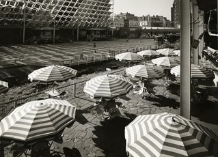 Black and white photograph of hooped table umbrellas with mid-twentieth-century architecture in the background. Design Council Archive Design Archives catalogue number GB-1837-DES-DCA-30-1-FOB-CO-12