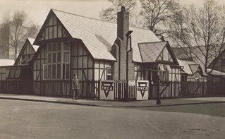 Sepia photograph across a road towards a single-storey mock-Tudor building with tall chimney stack. The former YMCA building known as the Shakespeare Hut.