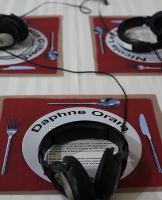 Detail of dinner service laid with sound listening devices, the foremost labeled with the name of digital music pioneer Daphne Oram.