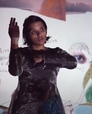 Rajyashree Ramamurthi directed by Billy Cowie poses during a performance wearing Indian dress and against iconographic Indian backdrop.