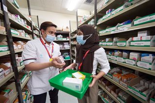 Man showing woman some medicine in pharmacy cupboard JPG