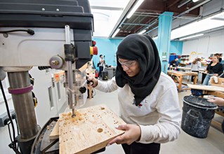 Student drilling wood in a studio