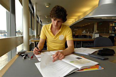 A student in front of some books in a university library
