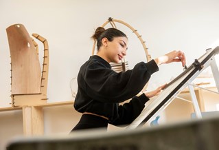 Female student drawing at draftsman table