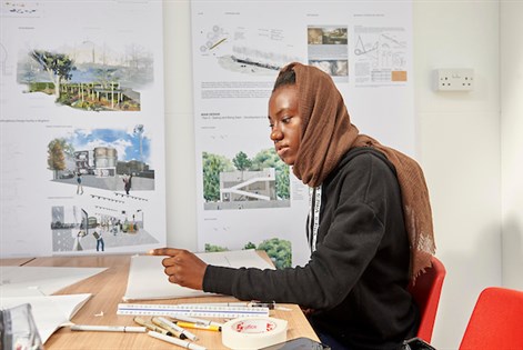 Female student drawing with work behind her
