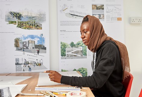 Female student drawing with work behind her