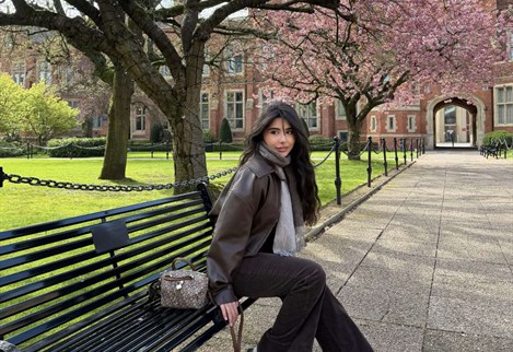 Architecture BA student Khalamana sat on a bench with a blossom tree in the background