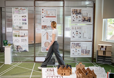 Interior design student walking through designs and models on display