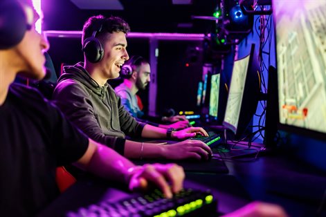 Gamers sit in a row, interacting with one anothe and the screen in front of them