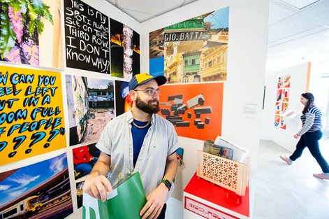 male student prepares colourful graphics and photos for graduate show