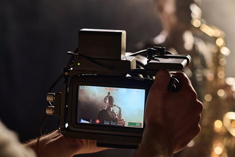 student looks at saxophone player through view screen of digital camera