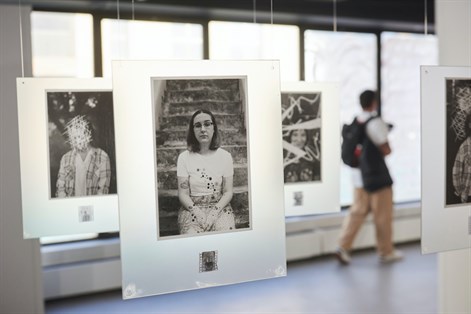 large black and white photo installation in gallery with visitor in background