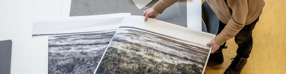 shot from above, student lays out large photos on a table