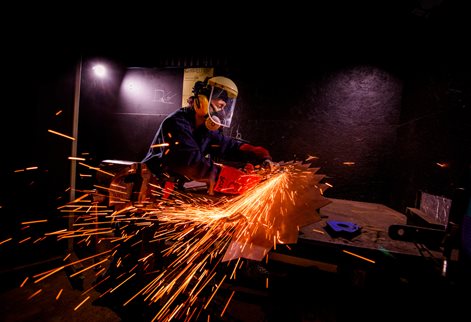 Student using metal work tools creating sparts