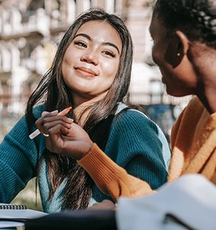 Two students studying outside and smiling