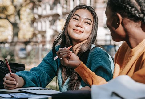 Two students studying outside and smiling