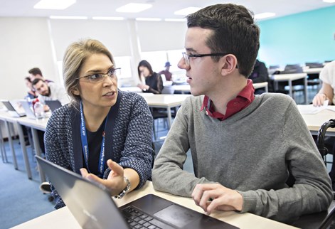 student and teacher in college setting looking at laptop