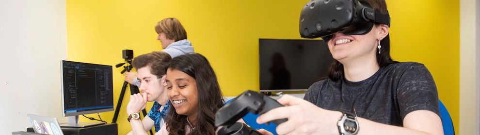 Female student wearing VR headset and three students on computers