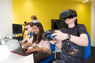 Female student wearing VR headset and three students testing software