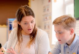 A teacher talking to a young pupil