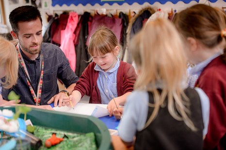 Male trainee taking part in drawing with group of school children